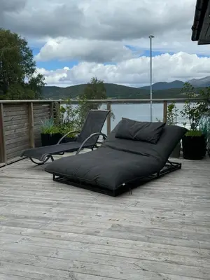 a bed sitting on a deck next to a lake at Villa med fantastisk uteplass! 10 sengeplasser! in Ålesund