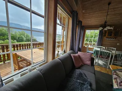 a living room with a couch and a large window at Øen Hytter 1 in Sørbø