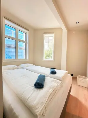 two beds in a room with two windows at Bergen City Apartment in Bergen