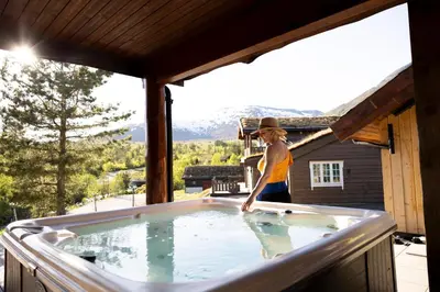 a woman standing in a hot tub on a porch at Spacious Mountain Lodge Stryn in Stryn