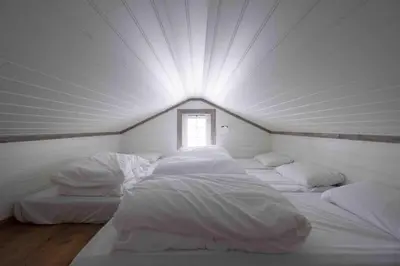 a room with four white beds with a window at Spacious Mountain Lodge Stryn in Stryn