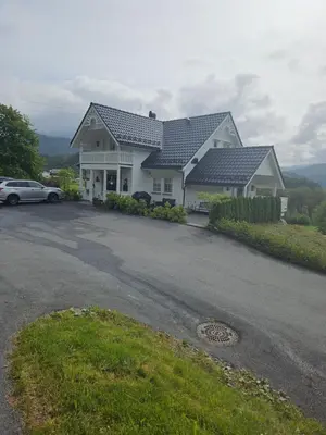 a house with a car parked in a driveway at Gårdsidyll i flotte omgivelser in Ålesund