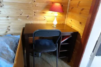 a desk with a lamp and a chair next to a bed at Guesthouse Hamran in Mosvik