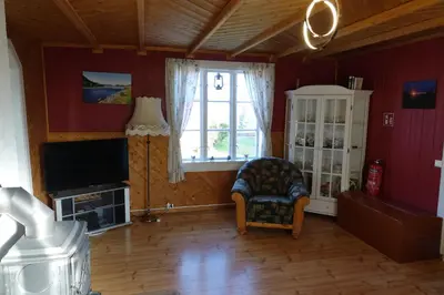 a living room with a chair and a television at Guesthouse Hamran in Mosvik