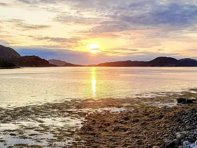 a sunset over a body of water with mountains at 6 person holiday home in Flatanger in Lauvsnes