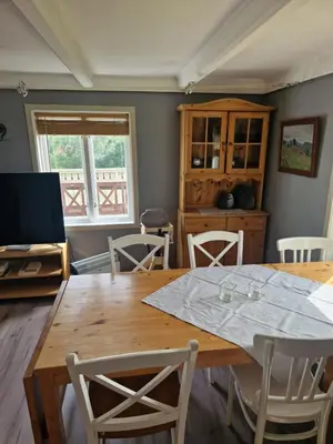 a dining room with a wooden table and chairs at Åsenfjord, feriehus ved sjøen in Hopla