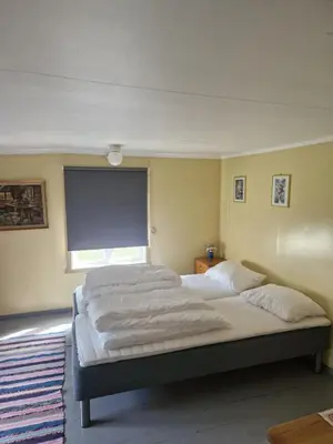 a bedroom with two beds and a large window at Åsenfjord, feriehus ved sjøen in Hopla
