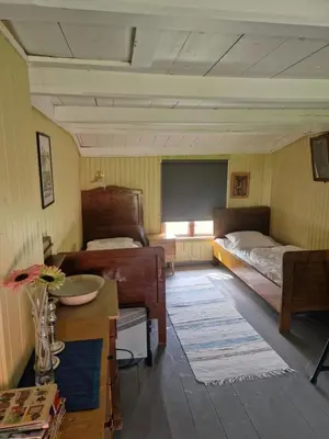 a room with two beds and a table and a window at Åsenfjord, feriehus ved sjøen in Hopla