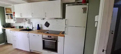 a kitchen with white cabinets and a white refrigerator at Åsenfjord, feriehus ved sjøen in Hopla