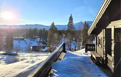 a snow covered porch of a house with a view of the mountains at Koselig Fjellhytte Med Utsikt in Bykle