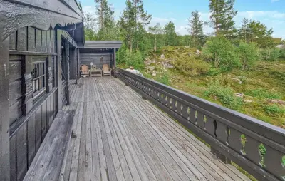 a wooden deck on a building with a table and chairs at Koselig Fjellhytte Med Utsikt in Bykle
