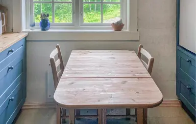 a wooden table in a kitchen with two chairs at Beautiful Home In Vassenden in Vassenden