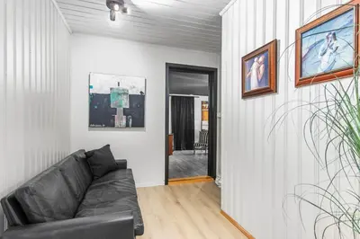 a living room with a black leather couch in a room at Skarnsundet apartment in Venneshamn