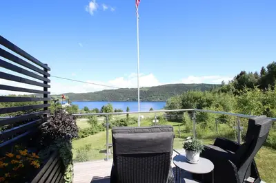a balcony with two chairs and a table with a view of a lake at Skarnsundet apartment in Venneshamn