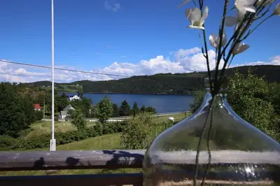 a glass vase with flowers in it with a view of a lake at Skarnsundet apartment in Venneshamn