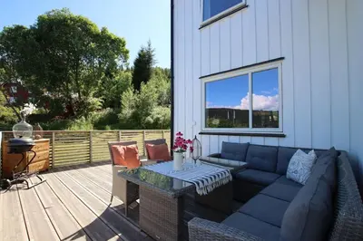 a patio with a couch and a table on a deck at Skarnsundet apartment in Venneshamn