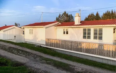 a white house with a fence next to a road at 3 Bedroom Nice Home In Kvenvær in Kvenvær