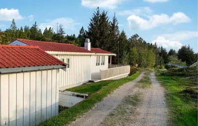 a dirt road next to a house with a fence at 3 Bedroom Nice Home In Kvenvær in Kvenvær