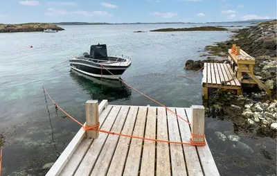 a boat is tied to a dock in the water at 3 Bedroom Nice Home In Kvenvær in Kvenvær