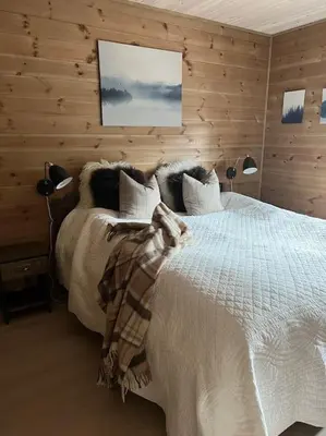 a bedroom with a large white bed with wooden walls at ChaletMons, stor trivelig leilighet i Myrkdalen in Vossestrand
