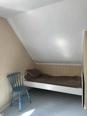 a bed and a blue chair in a room at Veslegarden in Lærdalsøyri