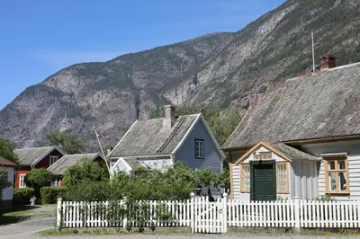 a house with a white fence in front of a mountain at Veslegarden in Lærdalsøyri