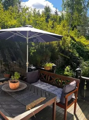 a wooden table with an umbrella on a patio at Koia Guesthouse in Flesberg