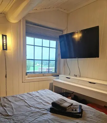 a bedroom with a large flat screen tv on the wall at Koia Guesthouse in Flesberg