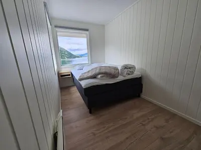a small bedroom with a bed and a window at Modern cabin with panorama view in Olden