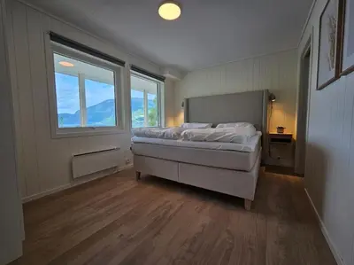 a bedroom with a bed and a large window at Modern cabin with panorama view in Olden