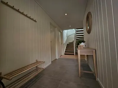 a hallway with stairs and a clock on the wall at Modern cabin with panorama view in Olden