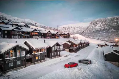 a red car parked in the snow in front of buildings at Rekkehus i Myrkdalen in Helgatun