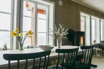 a dining room with a table with chairs and flowers at Leilighet Overøye Hyttegrend in Stordal