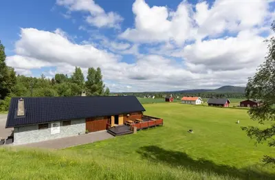 a barn with a green field and a house at Skogcamping in Bjørnstad