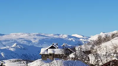a house covered in snow with mountains in the background at Panorama 4 C Ski Inn And Out With Views Of Slettefjell in Beitostøl