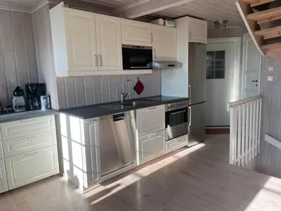 a kitchen with white cabinets and a black counter top at Panorama 4 C Ski Inn And Out With Views Of Slettefjell in Beitostøl