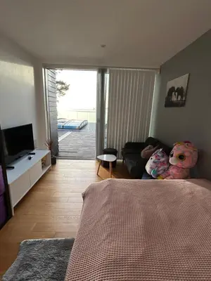 a bedroom with a living room with a couch and a television at Nydelig villa ved sjøen med oppvarmet basseng in Bergen
