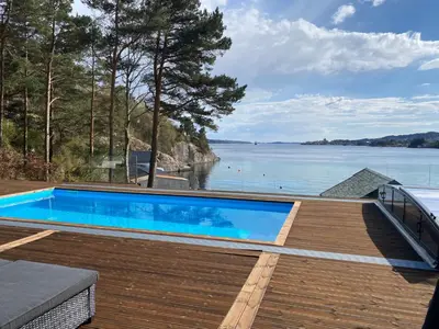 a swimming pool on a deck next to the water at Nydelig villa ved sjøen med oppvarmet basseng in Bergen