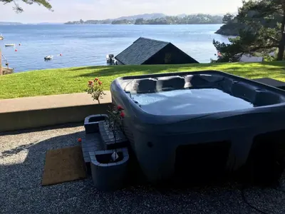 a large bath tub sitting next to a body of water at Nydelig villa ved sjøen med oppvarmet basseng in Bergen