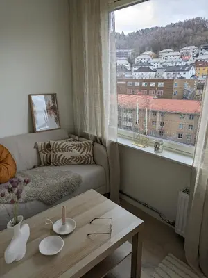 a living room with a couch and a table and a window at Meget hjemmekoseligISentraltINyoppusset leilighet in Bergen