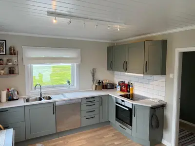 a kitchen with gray cabinets and a sink and a window at Sjønært feriehus, båt tilgjengelig for leie in Ålesund