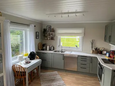 a kitchen with a sink and a table at Sjønært feriehus, båt tilgjengelig for leie in Ålesund