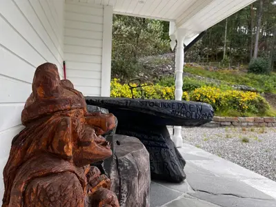 a statue sitting in front of a house at Fjord house with a private bay, boats and sauna! in Etnesjøen