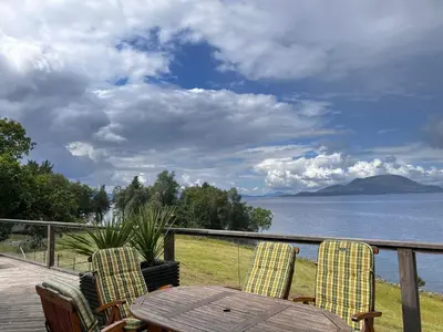 a table and chairs on a deck with a view of the water at Fjord house with a private bay, boats and sauna! in Etnesjøen
