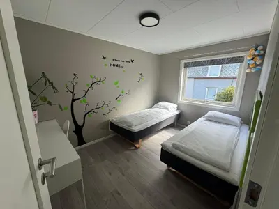 a hospital room with two beds and a tree mural at Ålesund sentrum apartment in Ålesund