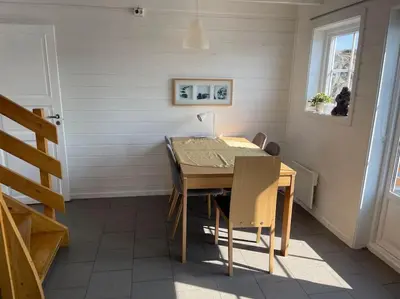 a dining room with a wooden table and chairs at Seaside apartment with balcony A1 in Nautnes
