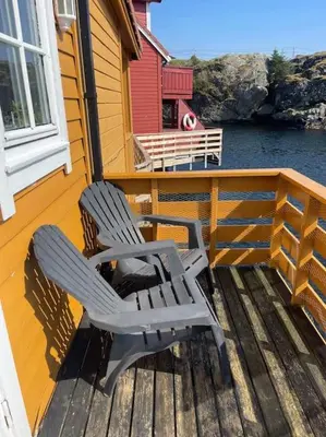 two chairs sitting on the deck of a house at Seaside apartment with balcony A1 in Nautnes