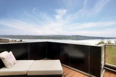 a balcony with a couch and a view of the water at Moderne og familievennlig bolig, nær populær strand ved Mjøsa in Gjøvik