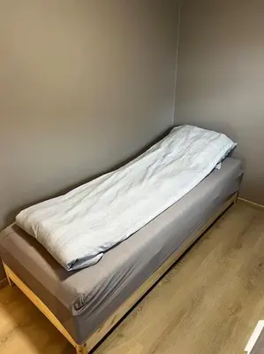 a bed sitting in a corner of a room at Nyoppusset leilighet midt i sentrum in Verdal