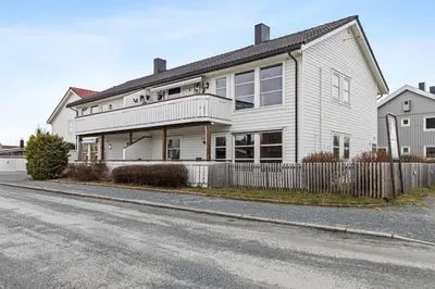 a white house on the side of a street at Nyoppusset leilighet midt i sentrum in Verdal